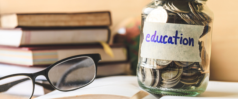 Glasses on a desk with money jar for education