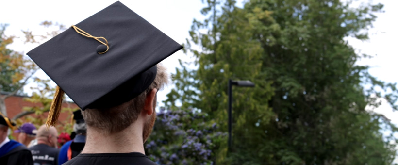 Student facing the crowd with graduation cap on