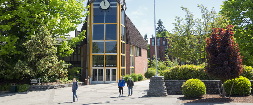 Students walking in the campus courtyard with clocktower building in background