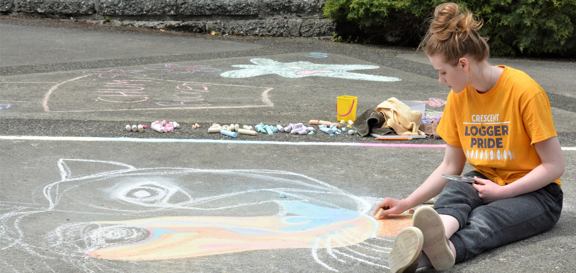 Student on cement drawing with chalk