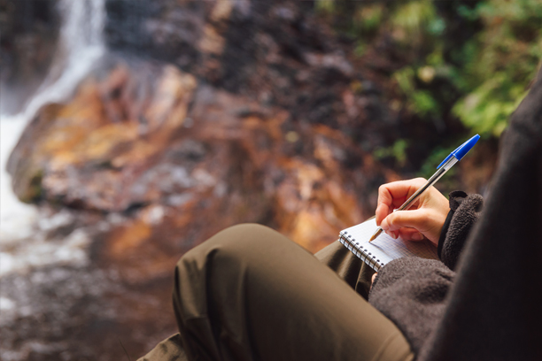 close up of person taking notes in woods