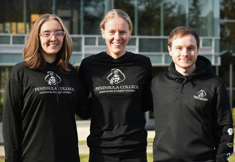 Three students standing on campus courtyard